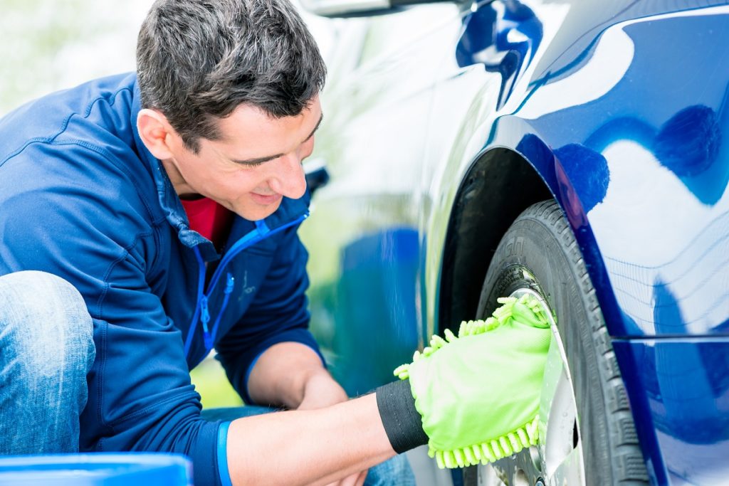 man cleaning car wheel