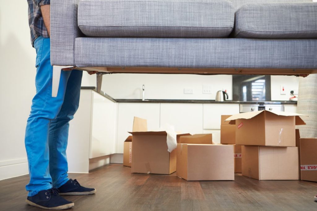 man carrying couch as he's moving in to his new home