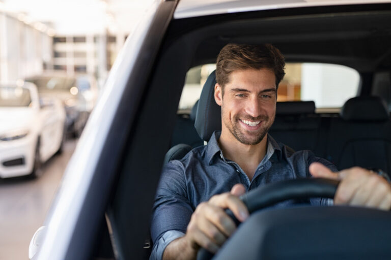 smiling male car enthusiast while test-driving the car in a dealer