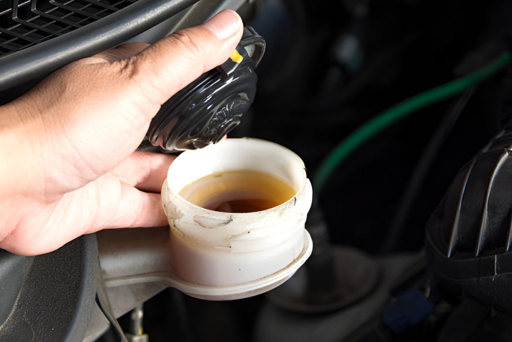 person holding the cap of a car's brake fluid reservoir