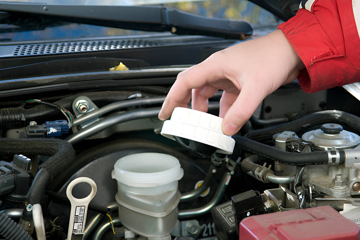 person holding a brake fluid reservoir cap