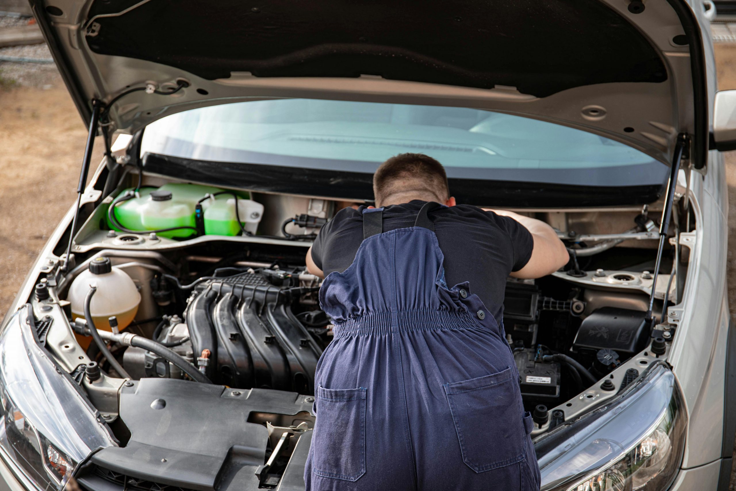 man under a car's open hood
